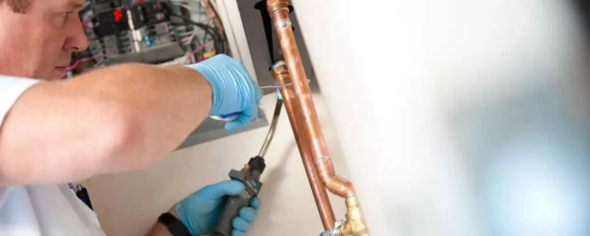 Water heater repair technician testing copper pipe connections and controls in Duluth, MN